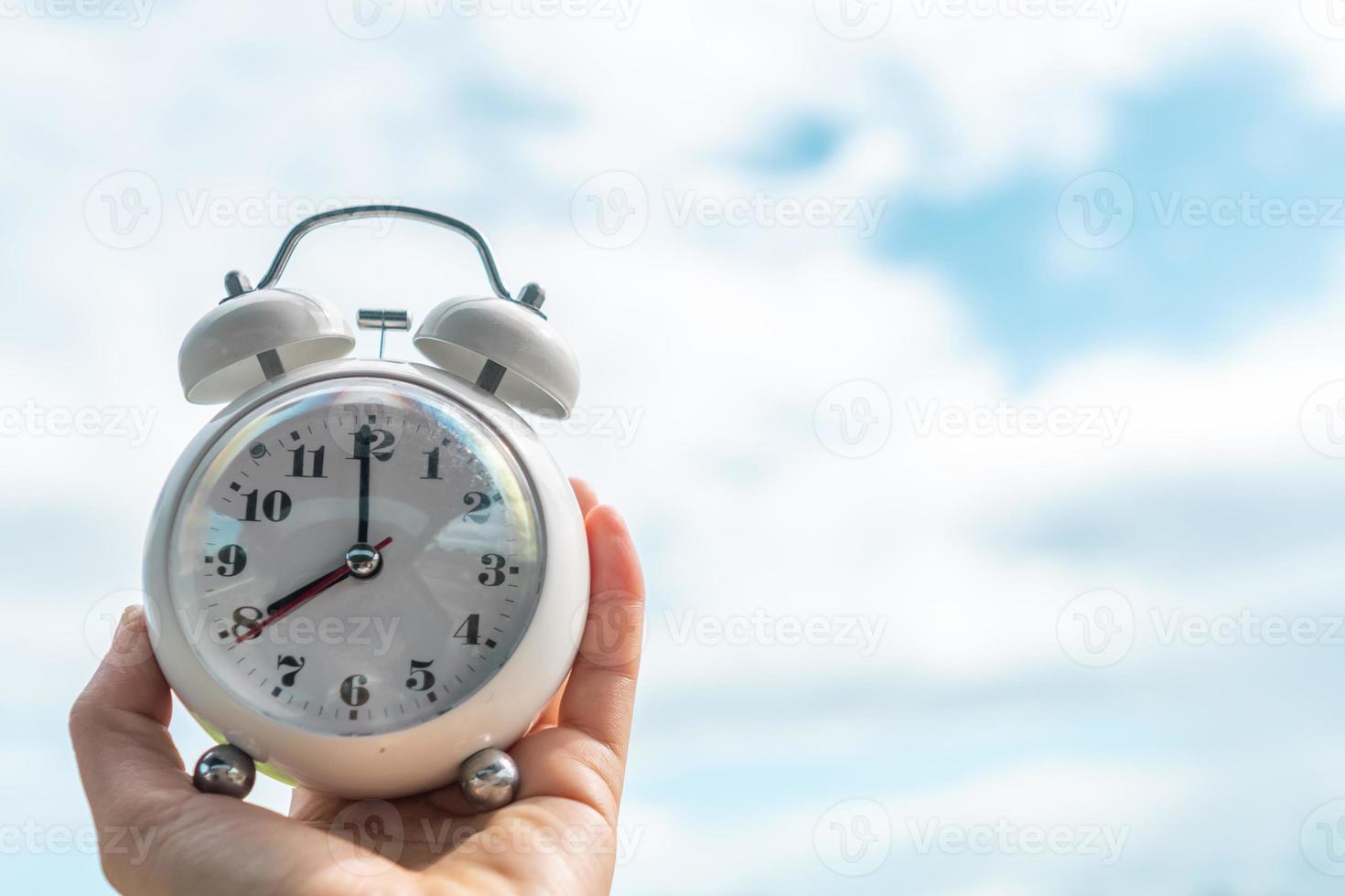 Selective focus of alarm clock with nature bokeh background. photo