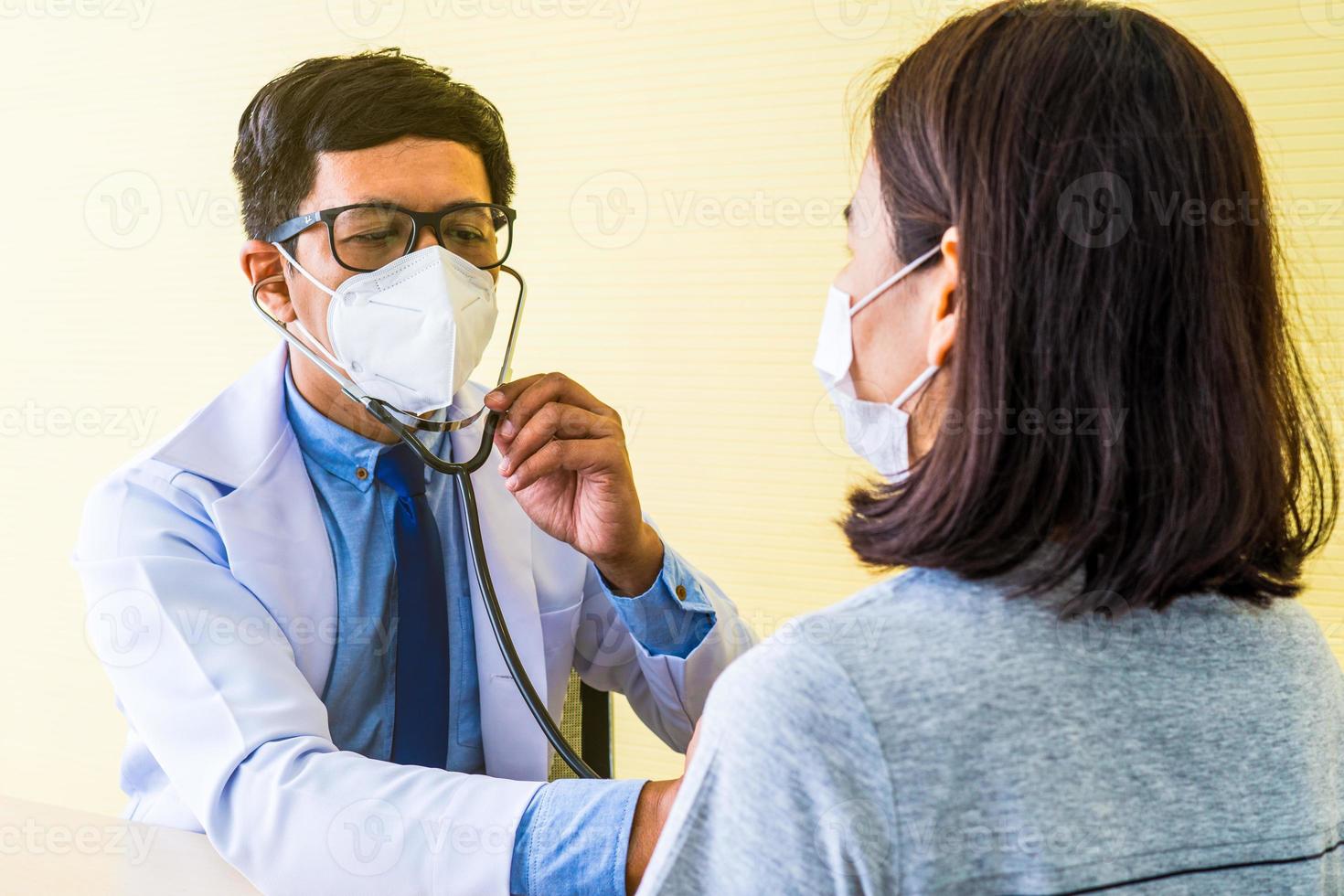 Doctor using stethoscope to listen to heart beat of patient photo