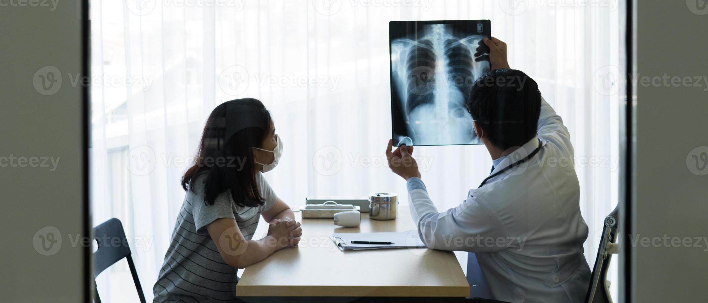 médico que muestra rayos x al paciente con máscaras en foto