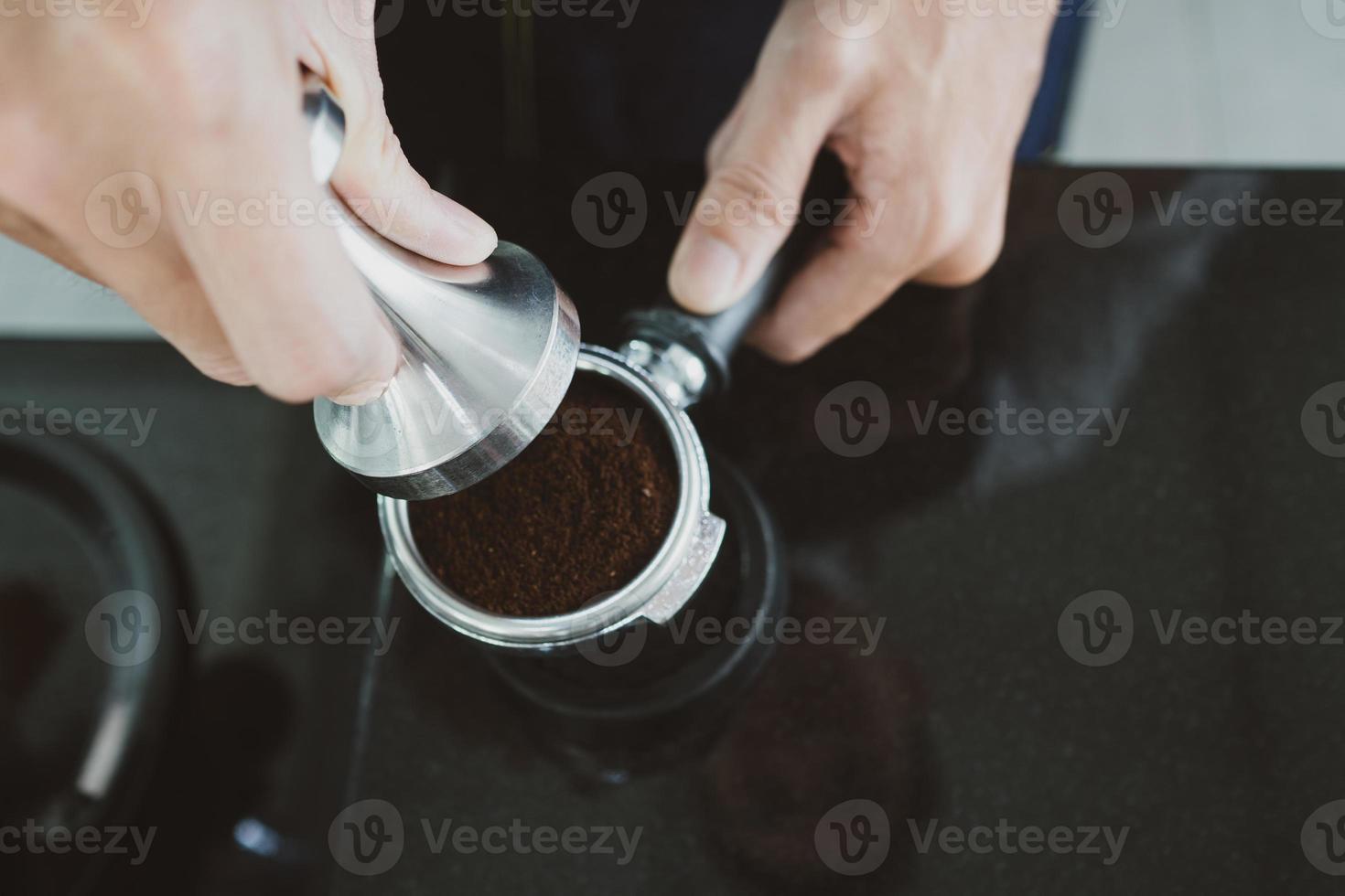 barista apisonando granos de espresso foto