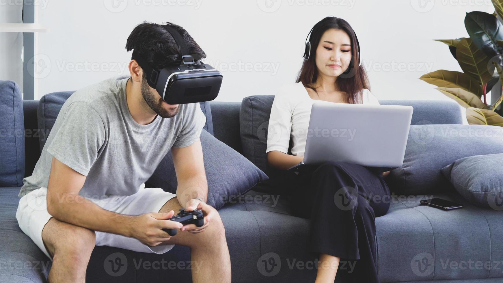 Man playing a virtual reality game while woman is working from home photo