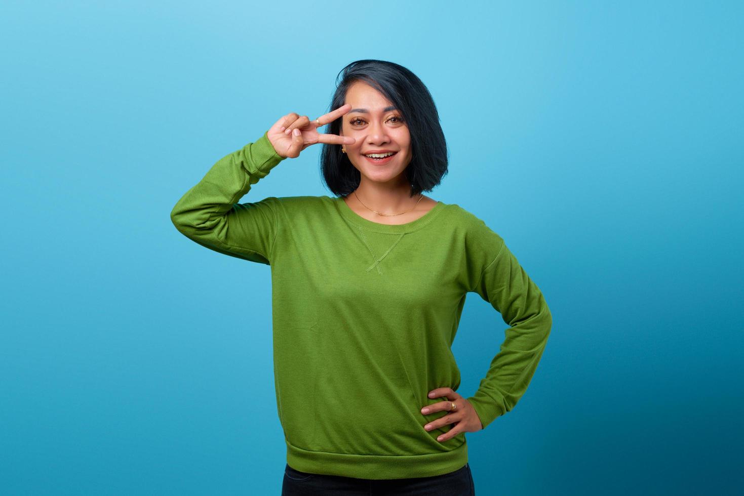 Beautiful Asian woman showing peace sign over eye and smiling photo