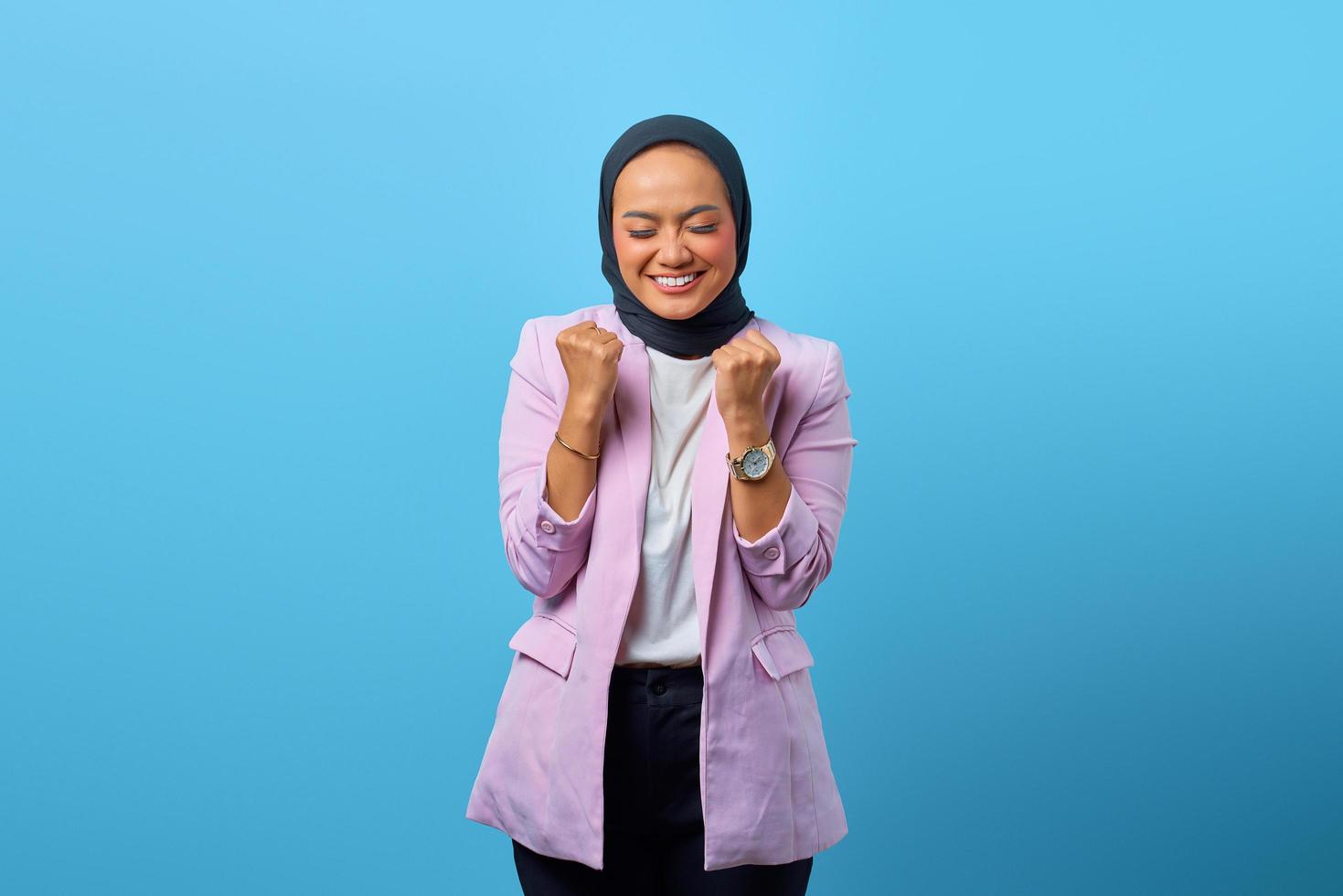 Emocionada mujer asiática celebrando la suerte y haciendo el gesto de la victoria foto