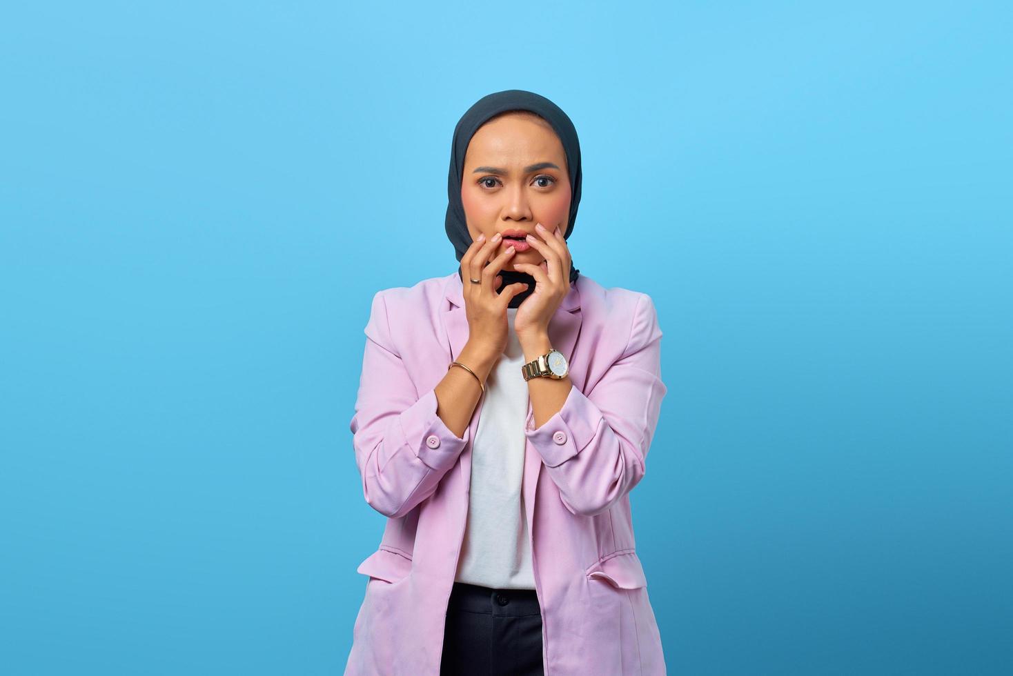 Beautiful Asian woman being scared of something over blue background photo