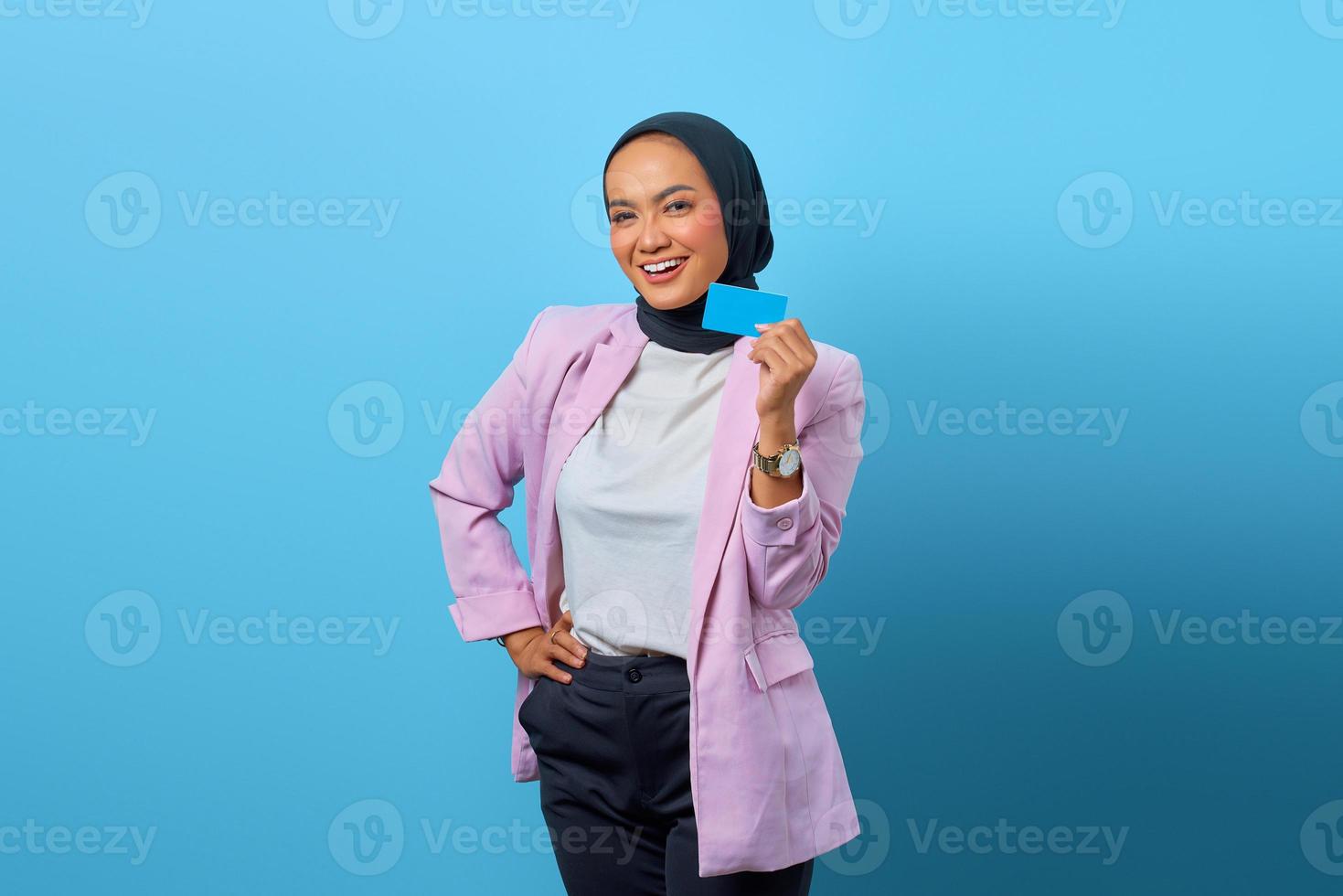 Hermosa mujer asiática sonriendo mientras muestra la tarjeta de crédito en la mano foto