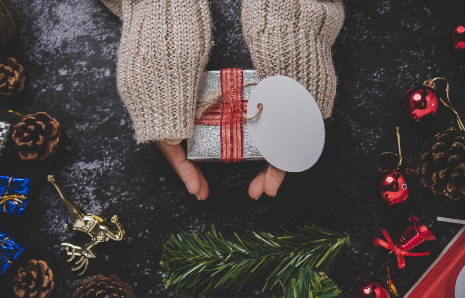 Mano sosteniendo una caja de regalo negra sobre un fondo de yeso negro foto