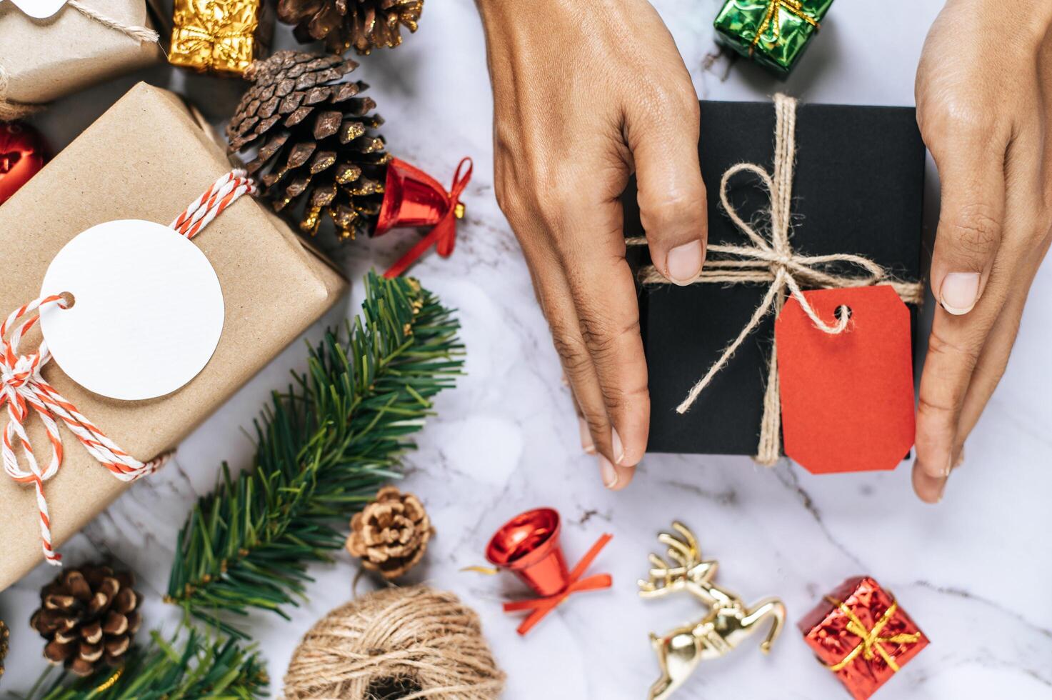 A hand holding a black gift box on a white cement floor photo