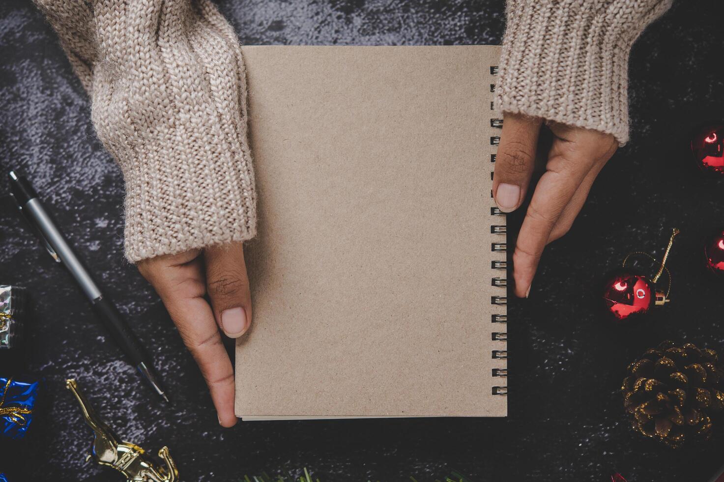 Hand holding a notebook with pen and small gifts photo