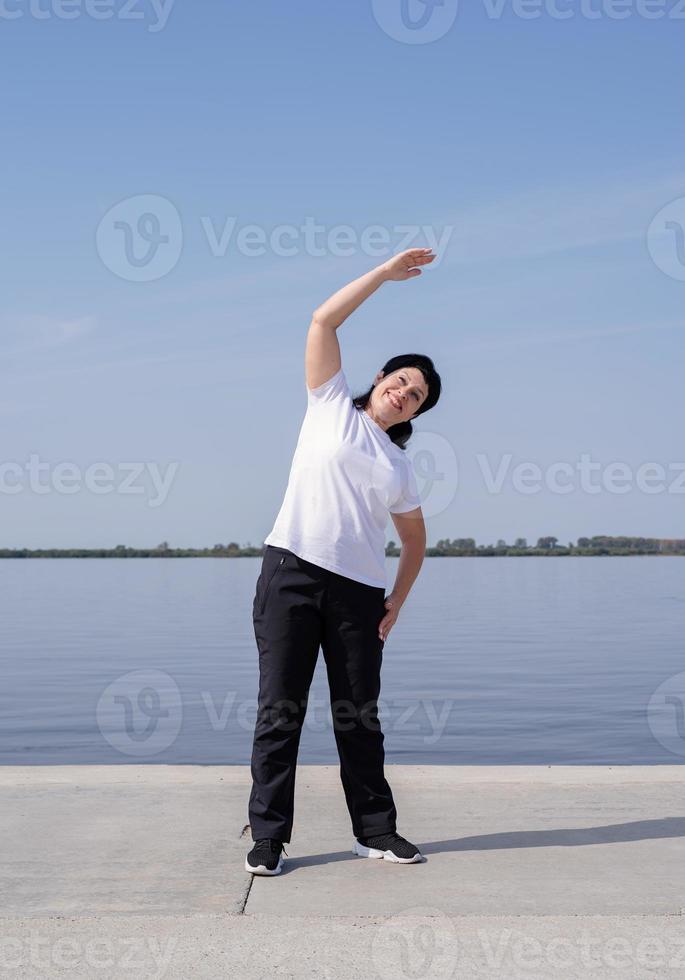 mujer mayor activa y feliz haciendo ejercicio cerca de la orilla del río foto