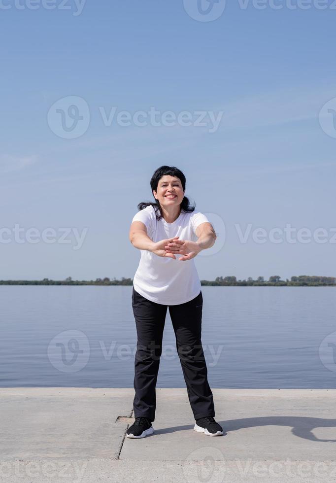 mujer mayor activa y feliz haciendo ejercicio cerca de la orilla del río foto