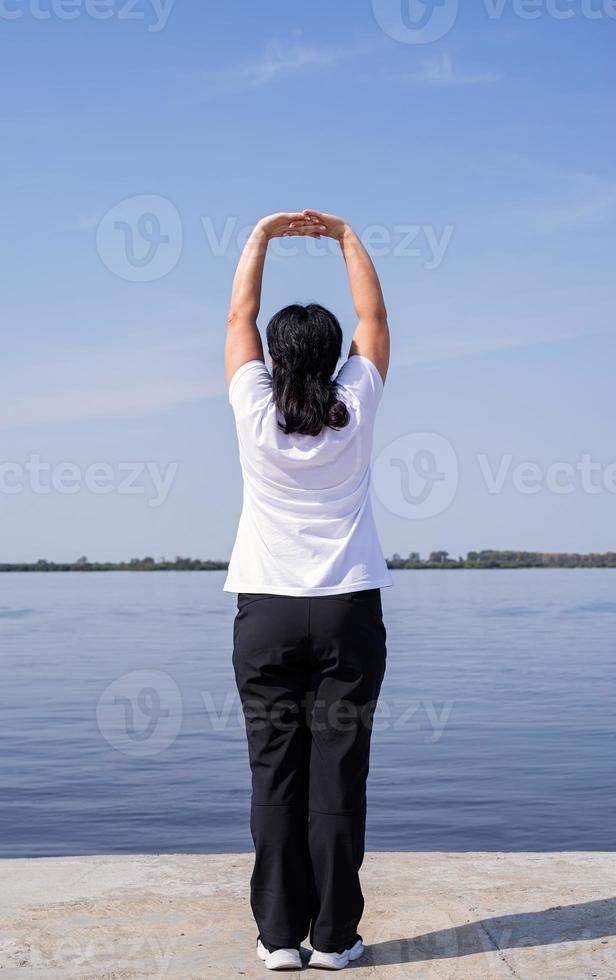 Active and happy senior woman exercising near the riverside photo