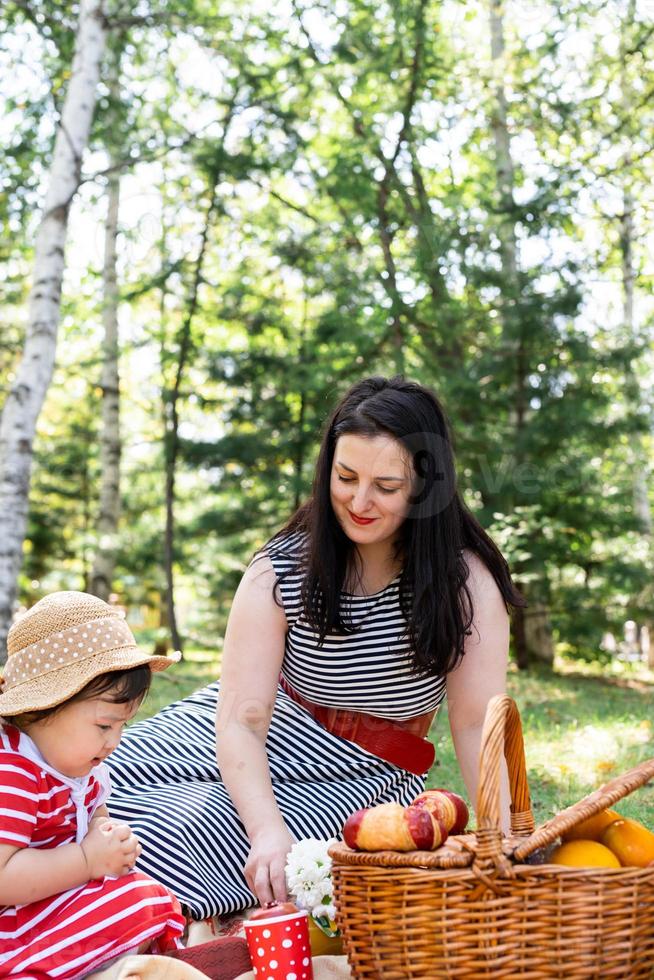 Familia interracial de madre e hija en el parque haciendo un picnic foto