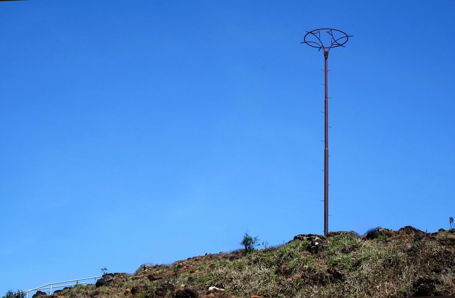 A tall post on a hilltop viewed against rich blue sky photo