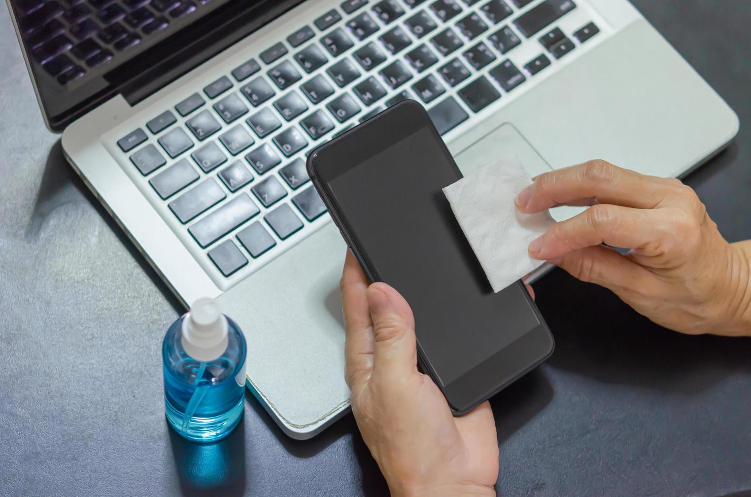 limpie y desinfecte su teléfono móvil con alcohol. concepto de salud foto