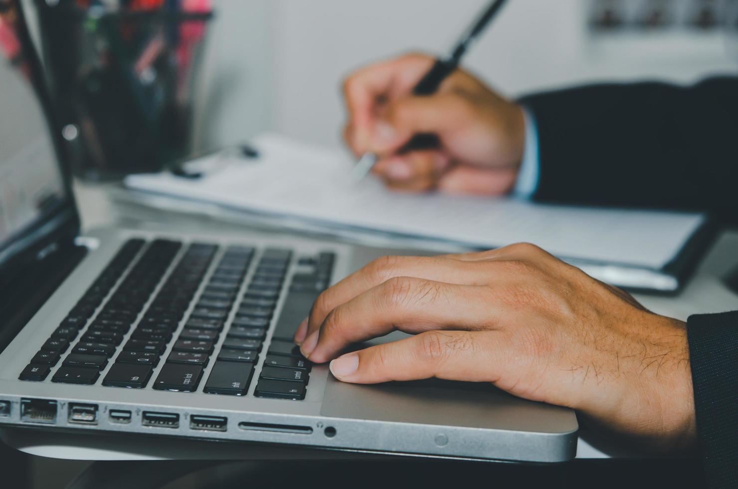 Cerrar la mano escribiendo en el teclado de la computadora portátil foto