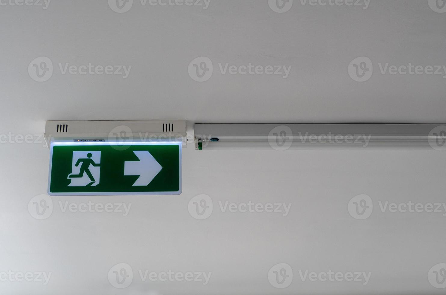 Exit signs, fire exits and arrows pointing the way on the ceiling photo