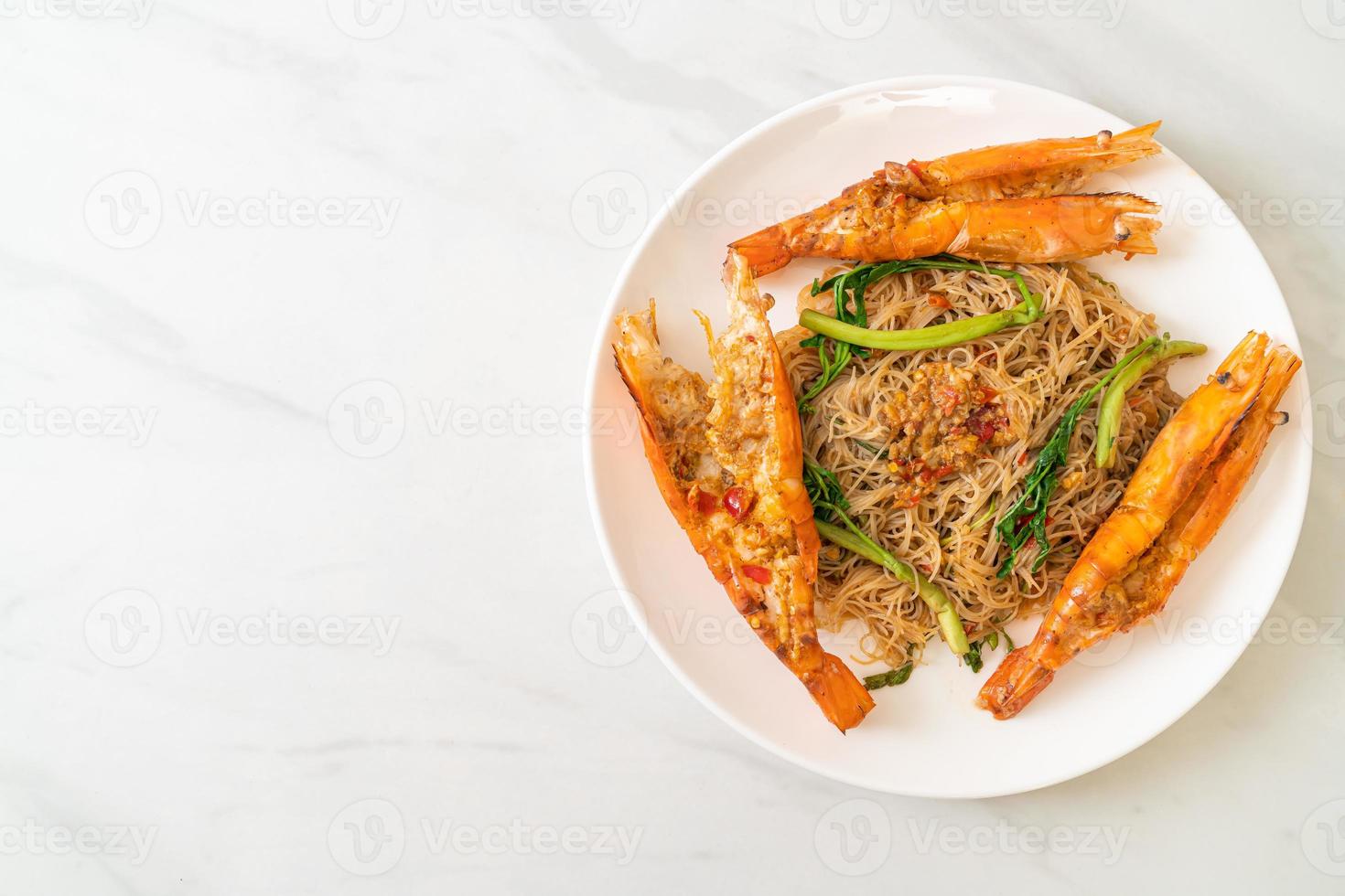 Fideos de arroz salteados y mimosa de agua con gambas de río foto