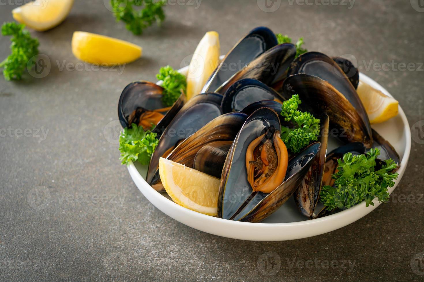 mejillones con hierbas en un bol con limón foto