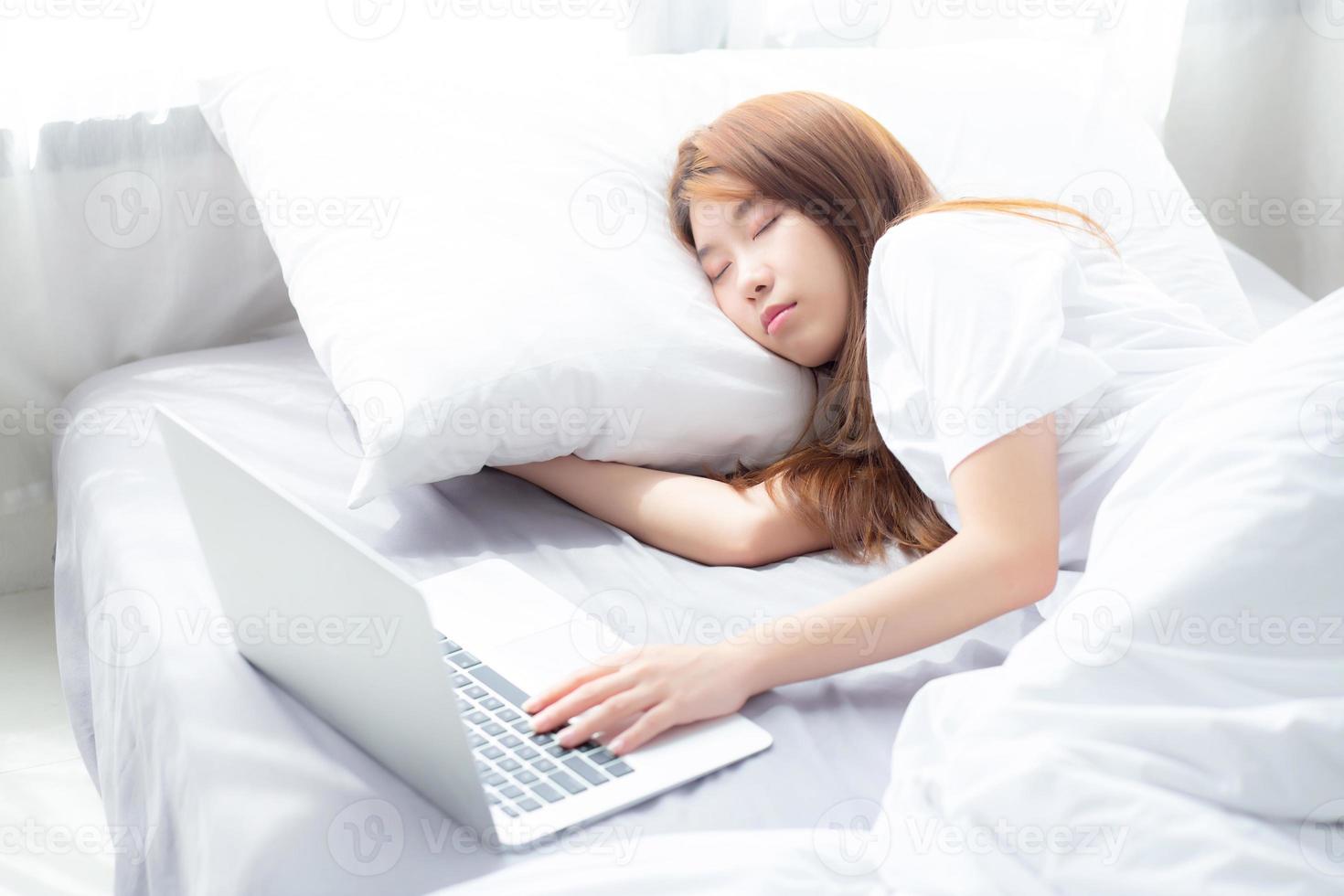 hermoso de retrato joven mujer asiática con laptop acostada en el dormitorio, niña cansada de dormir y relajarse con computadora portátil, descanso y concepto de salud. foto