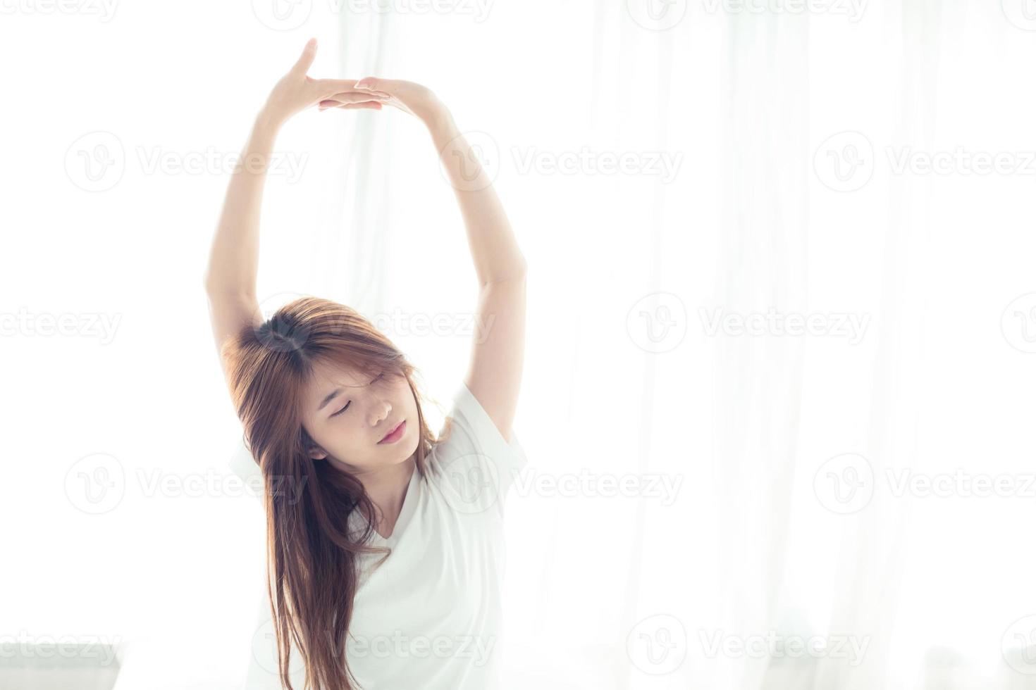 Young Asian woman stretch and relax in bed. photo