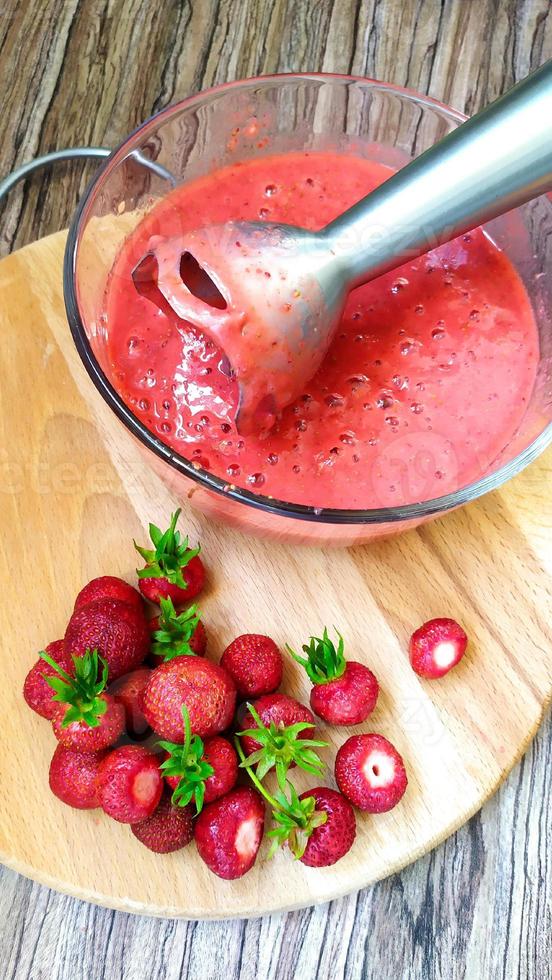 hacer un batido de frutas de fresa madura con una batidora eléctrica. foto