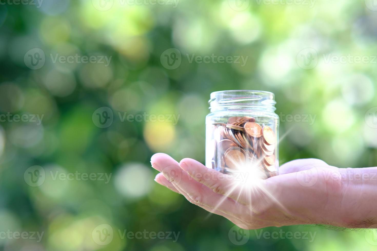 Saving money concept, hand holding coin in jar photo