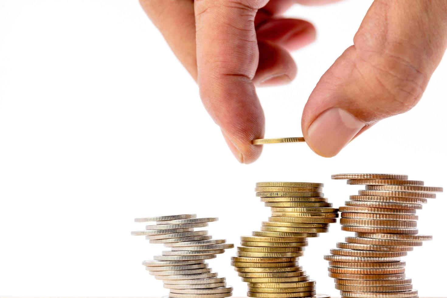 Closeup of human hand putting a coin on a pile of coins. photo