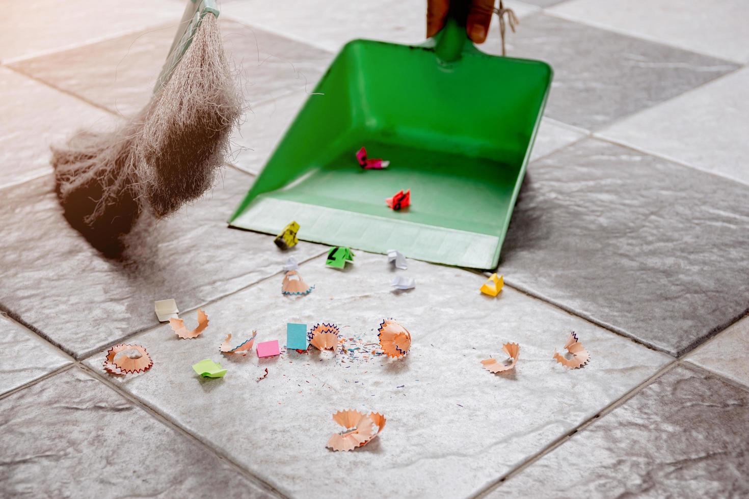 Sweep up scraps of paper tile floors with a broom and a dustpan. photo