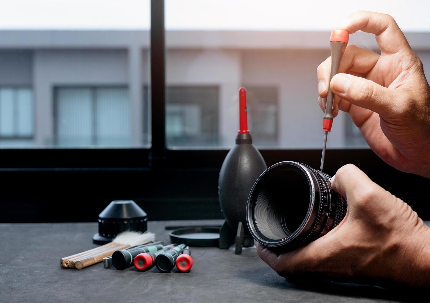 Using a screwdriver to remove screws on the barrel of a camera lens. photo