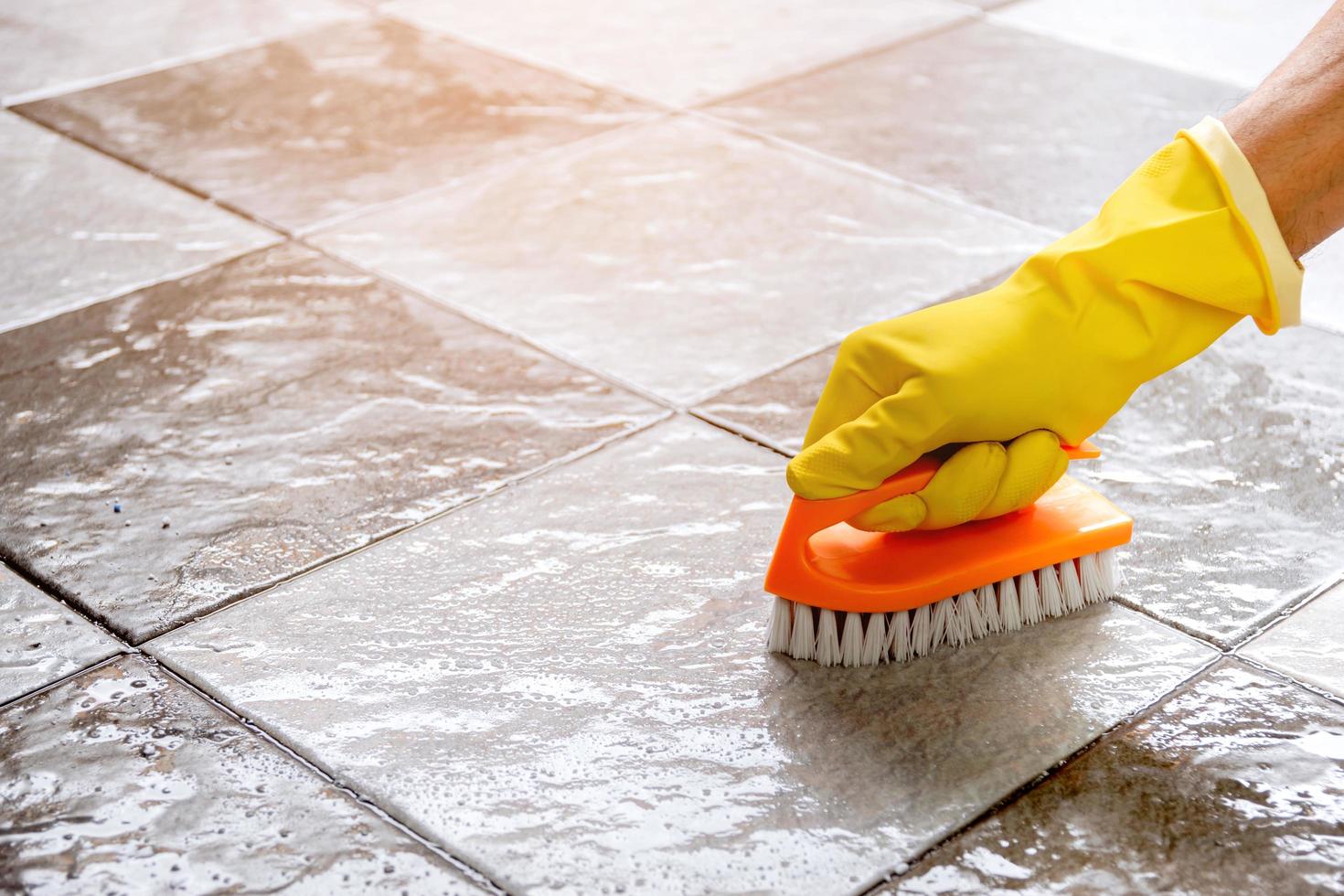 Using a plastic floor scrubber to scrub the tile floor. photo