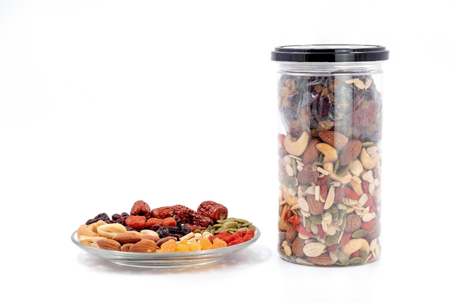 Whole grains and dried fruit in a glass plate and plastic bottle. photo