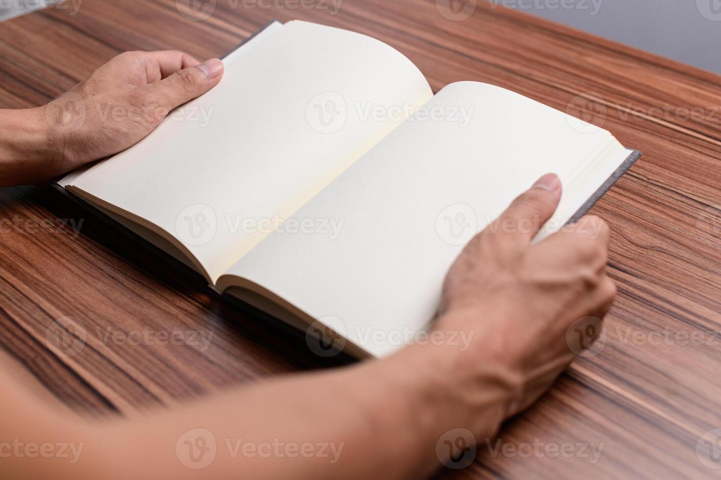 Close up of man's hands holding open book on wooden table photo