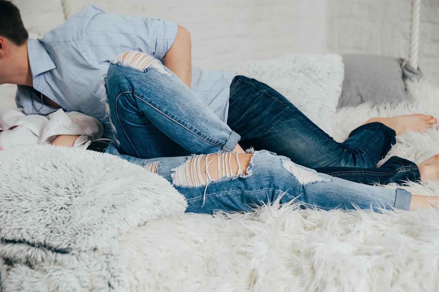 A couple in jeans and shirts on a white hanging bed photo