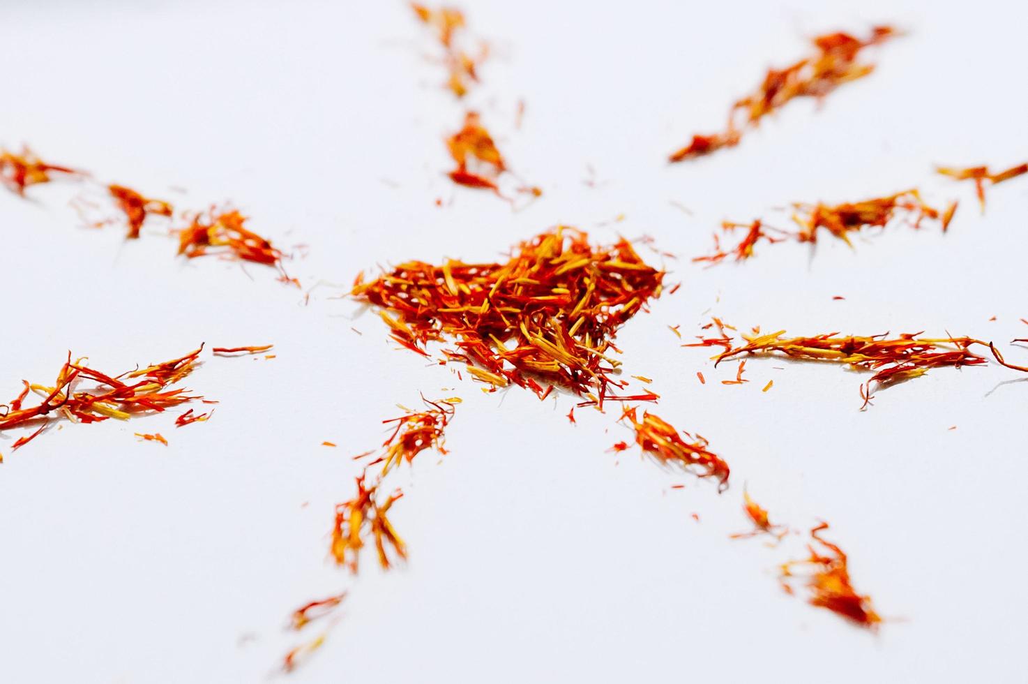 Selective focus close up Red Saffron in shape of mandala with heart on white background. Delicate flower threads. Natural healthy spice. For cafe menu or catalog photo