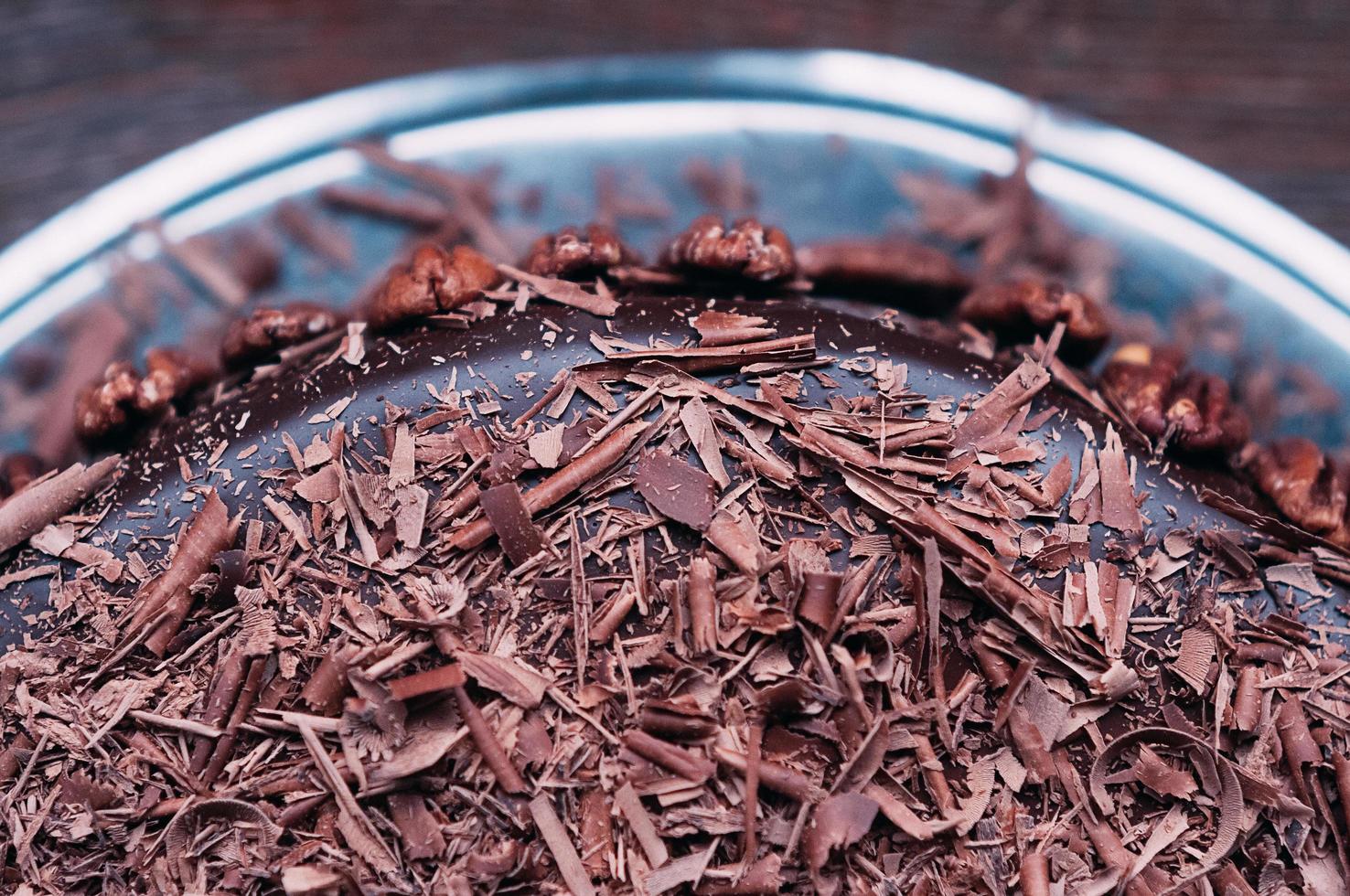 Macro view of delicious dark chocolate cake with beautiful icing and pecan nuts on the side on the brown wooden table. Selective focus. Luxurious glaze. Image for menu or confectionery catalog photo