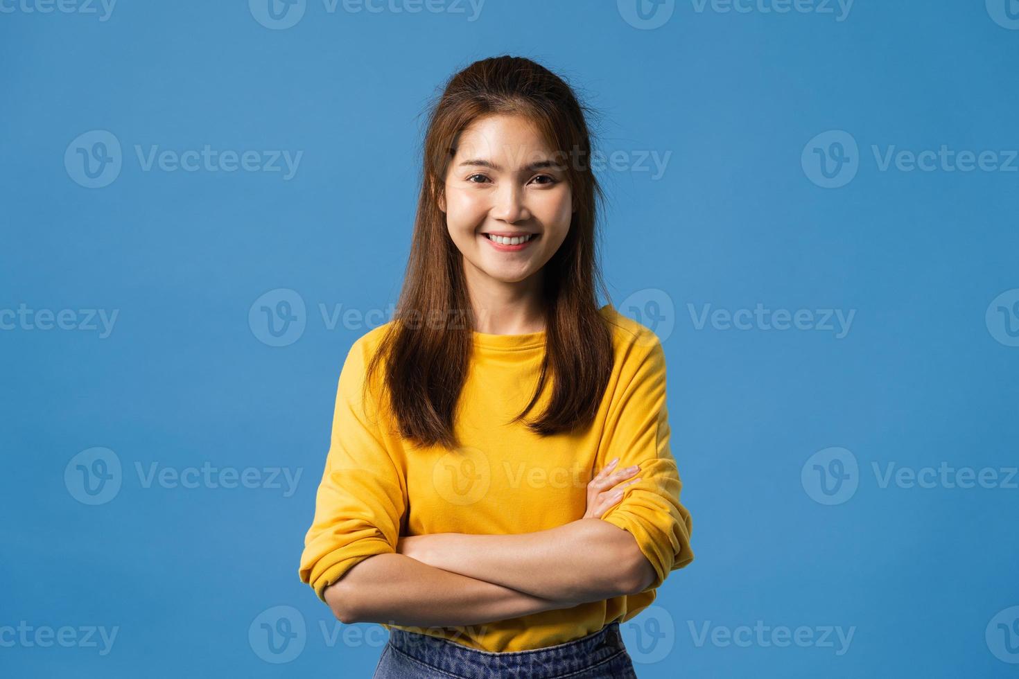dama asiática con expresión positiva, brazos cruzados sobre fondo azul. foto