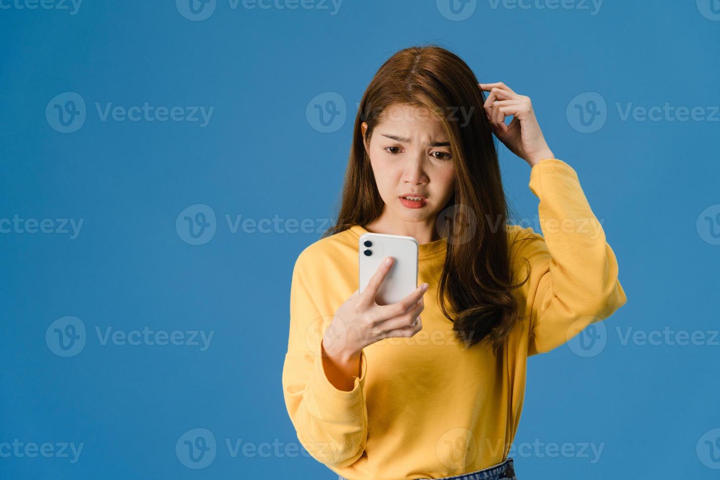 Thinking dreaming young Asia lady using phone on blue background. photo