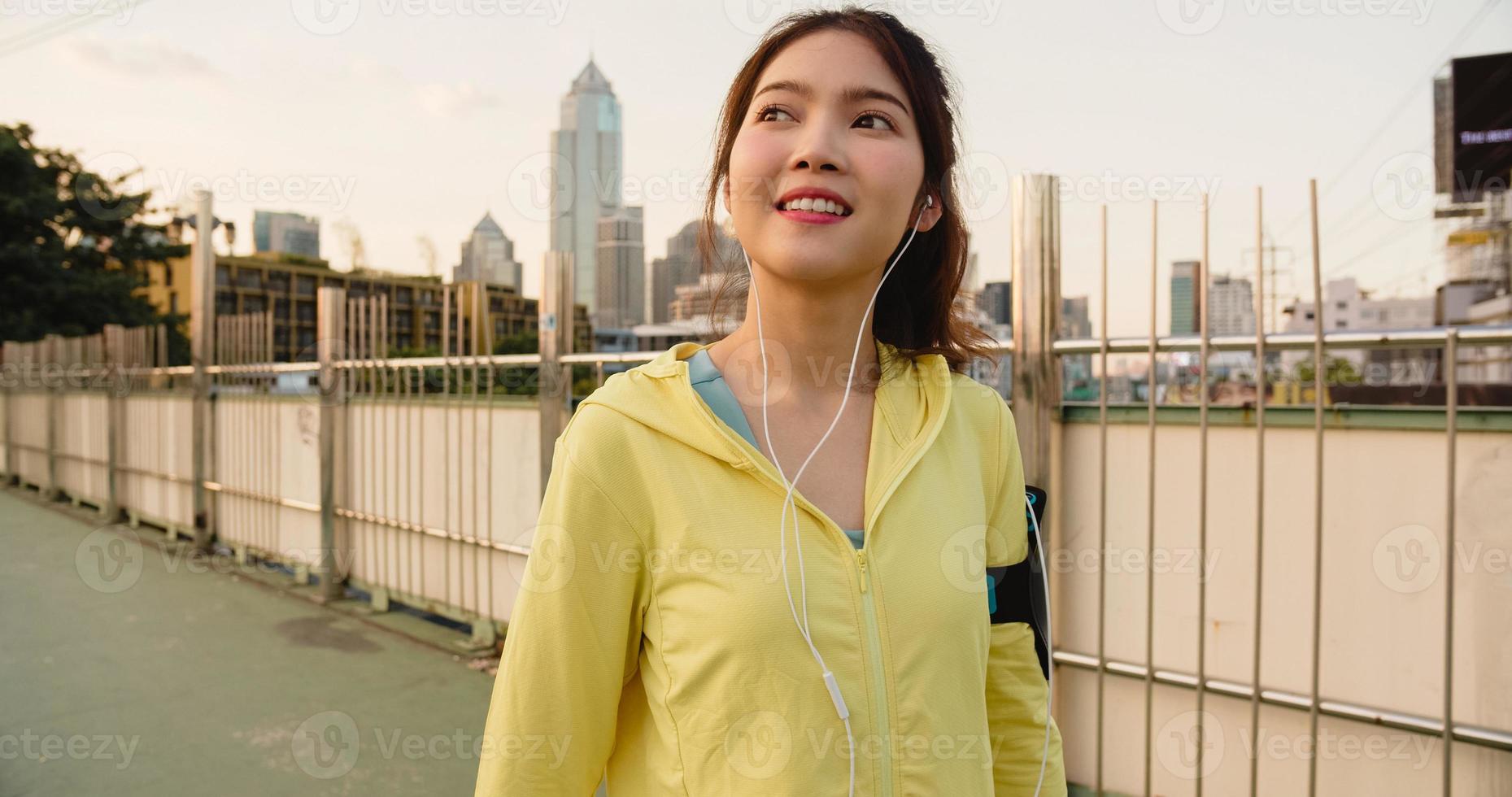 Asia atleta dama ejercicios con teléfono inteligente para escuchar música. foto