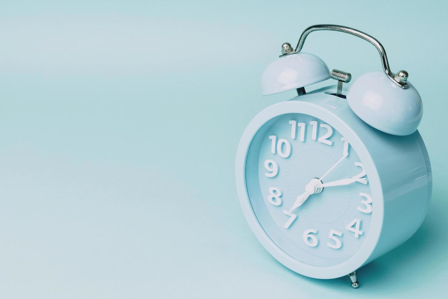 Alarm clock on blue paper background. Minimal-concept. photo