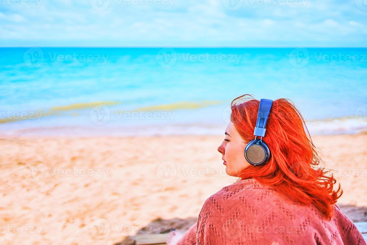 Beautiful woman listening to music on the beach photo