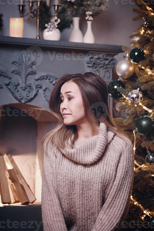 niña triste en suéter entre adornos navideños foto