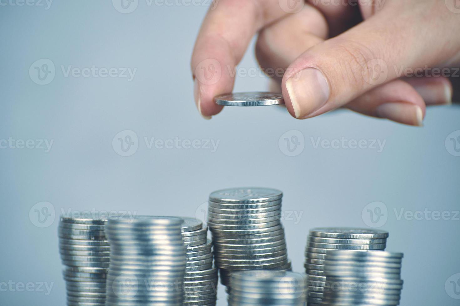 Woman's hand puts silver money coins to stack photo