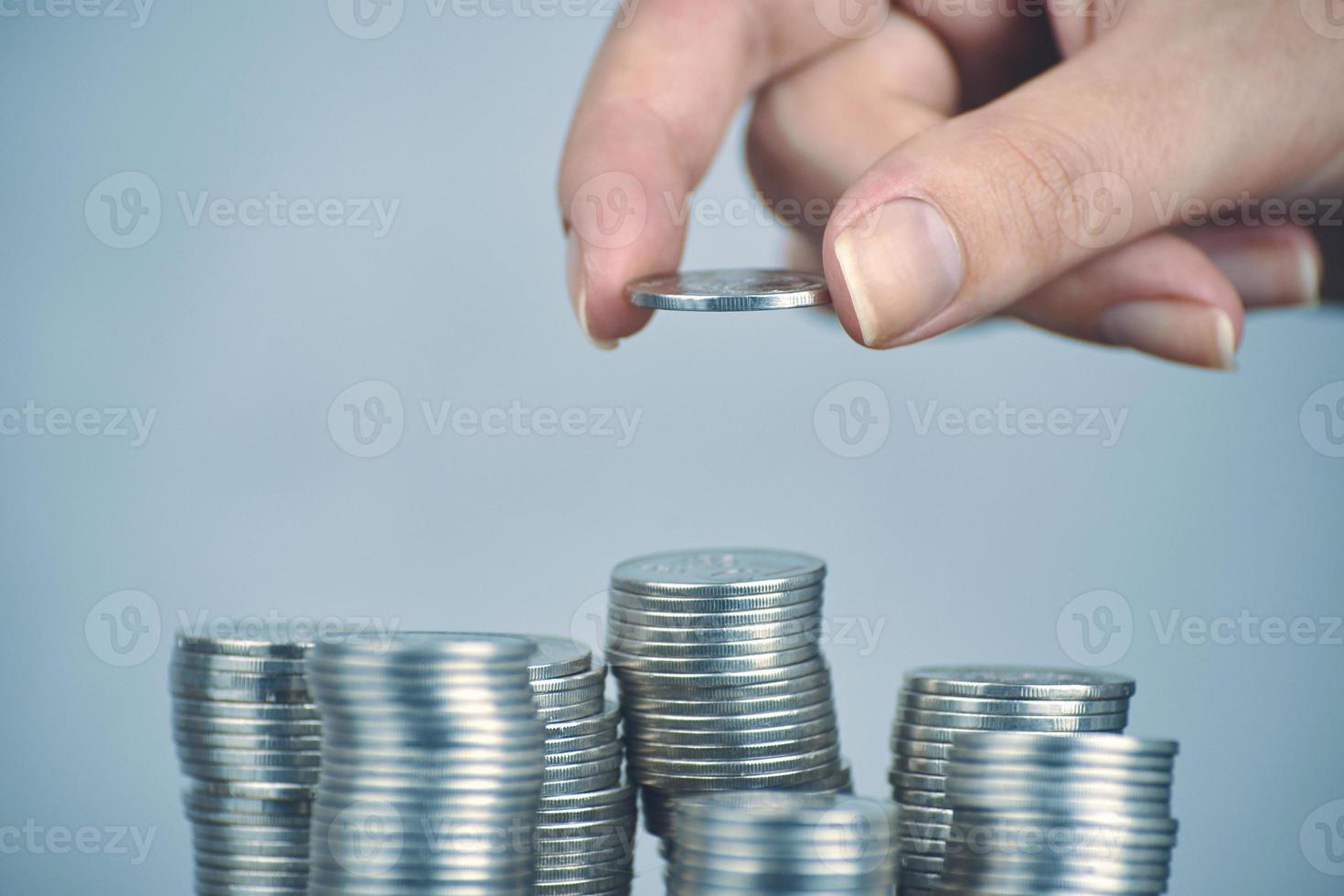 La mano de la mujer pone monedas de plata para apilar. foto