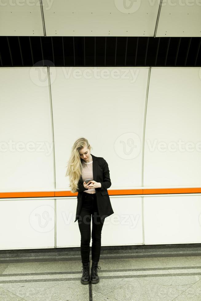 Pretty young woman with mobile phone in a subway photo