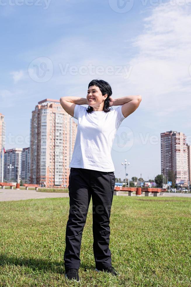 Mujer calentando al aire libre en el parque sobre fondo urbano foto