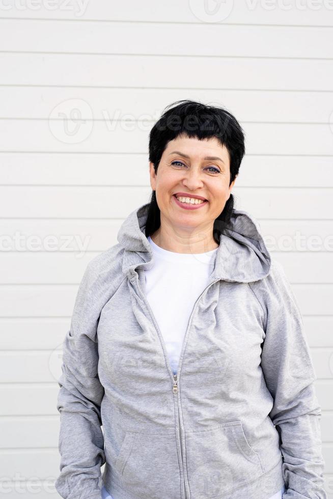 Mujer vistiendo chaqueta gris de pie al aire libre sobre fondo gris sólido foto