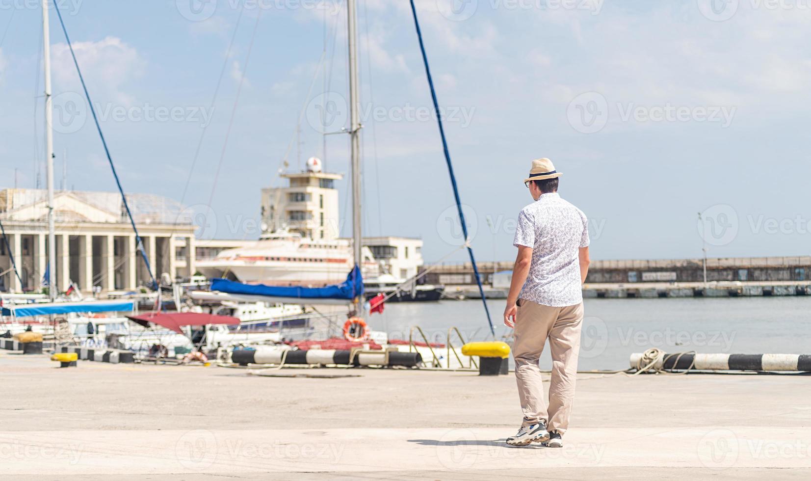 Turista caminando en el puerto marítimo, barcos y yates en el fondo foto