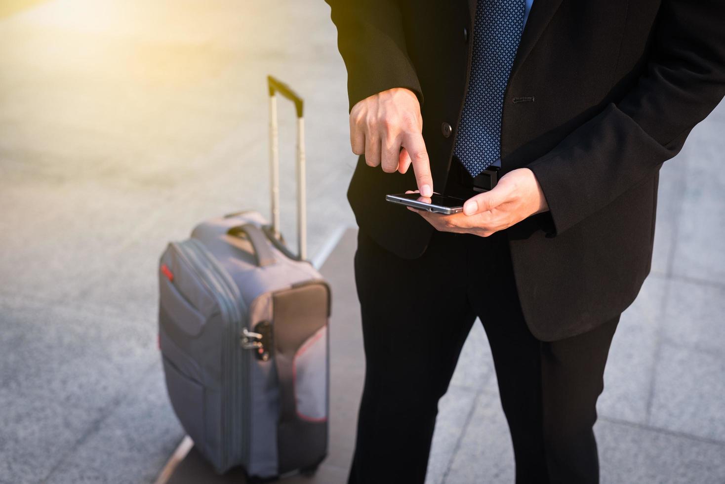 Businessman using smartphone with suitcase. photo