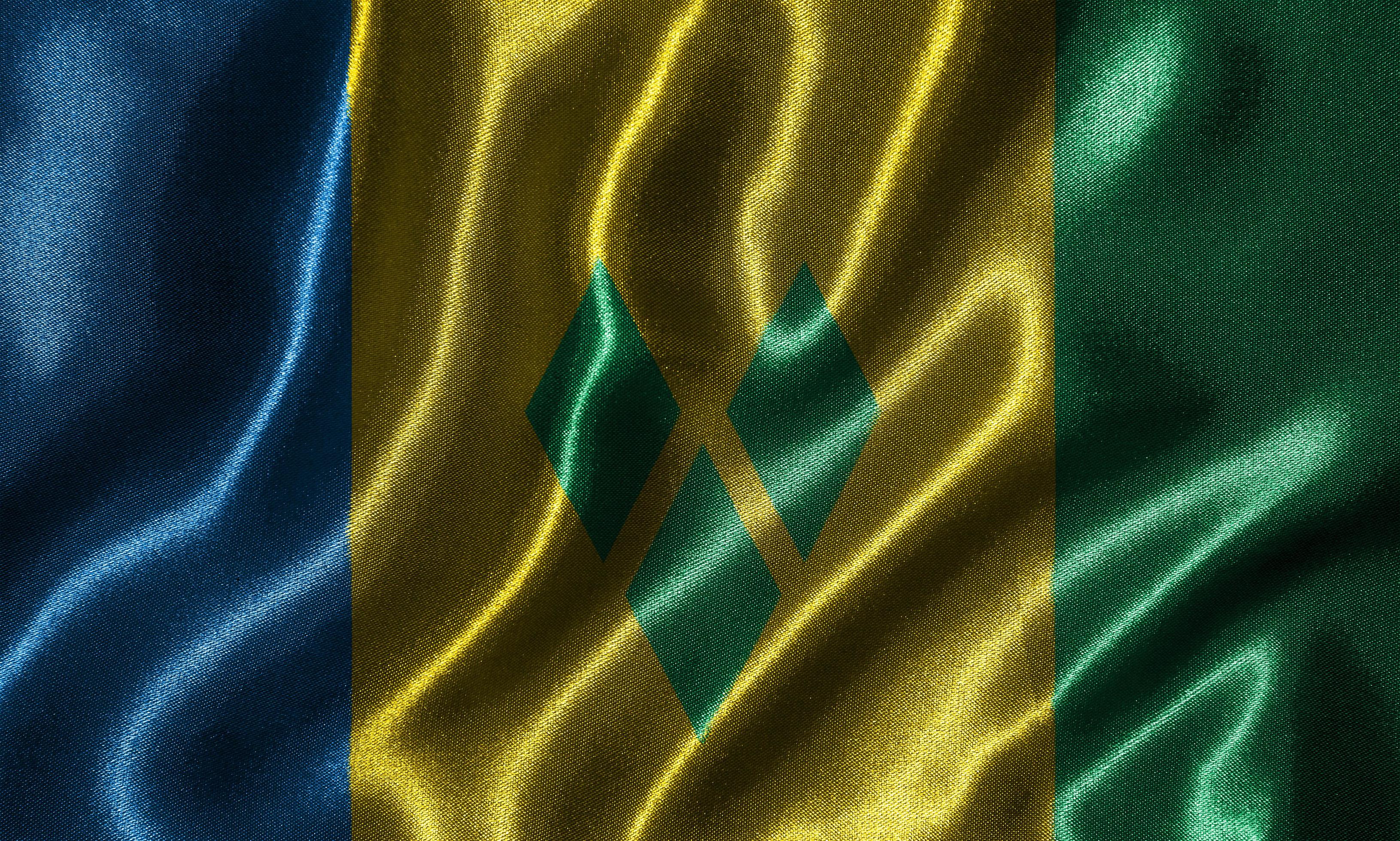 papel pintado de la bandera de san vicente y granadinas y bandera ondeante. foto