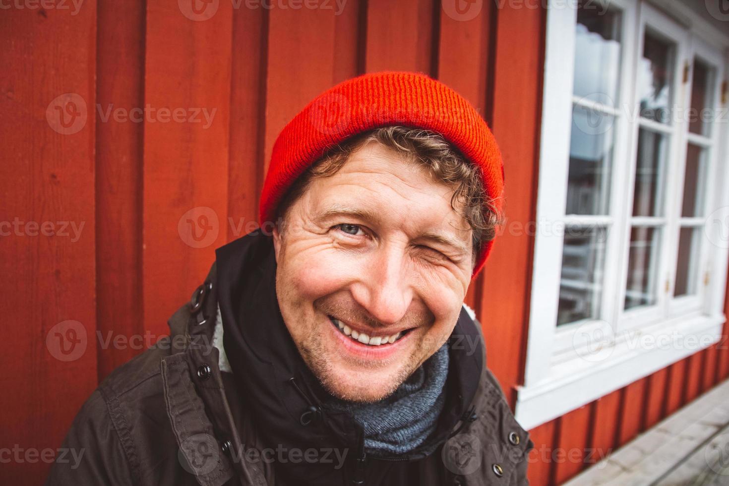 Retrato hombre viajero se sienta cerca de la casa de madera de color rojo. foto